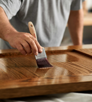 A pro painter applies finish to a piece of wood furniture