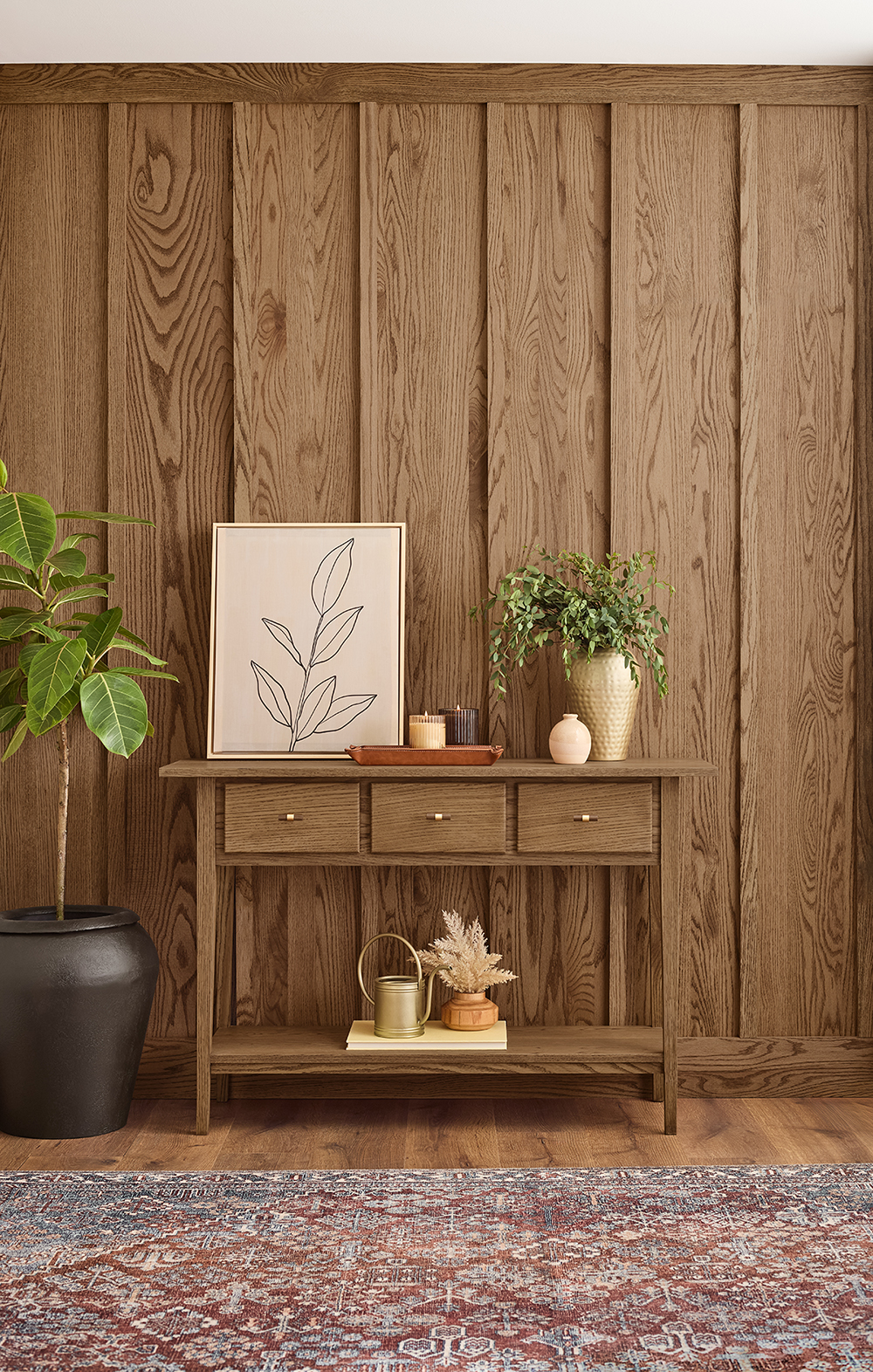Stained wainscoting behind a side table with artwork and plants.